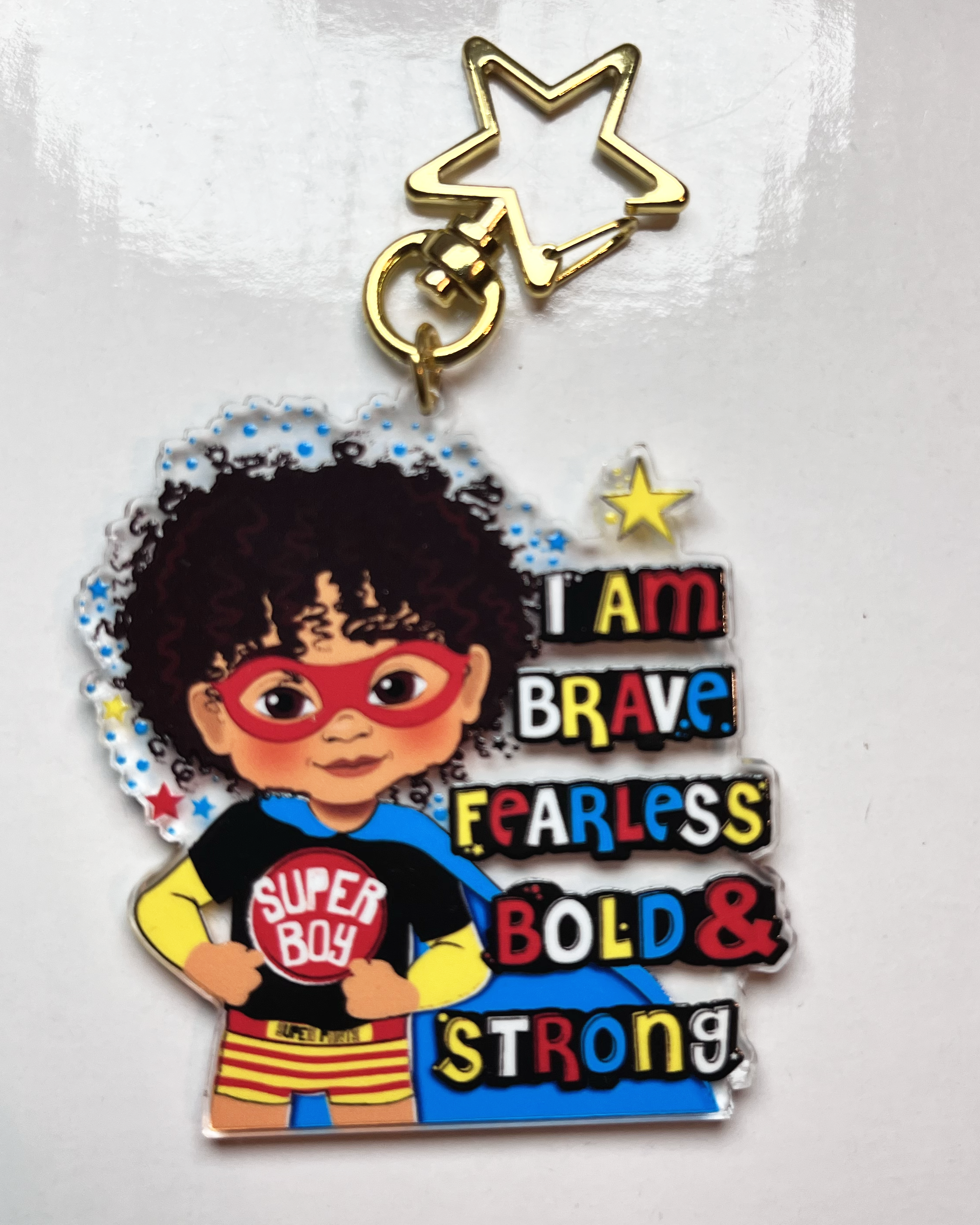 Keychain with a superhero-themed character and motivational text on a white background