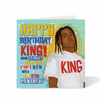 Teen boys Birthday card with a black boy wearing a 'King' shirt and celebratory colourful text 'Happy Birthday King' on a blue background by Fefus Designs
