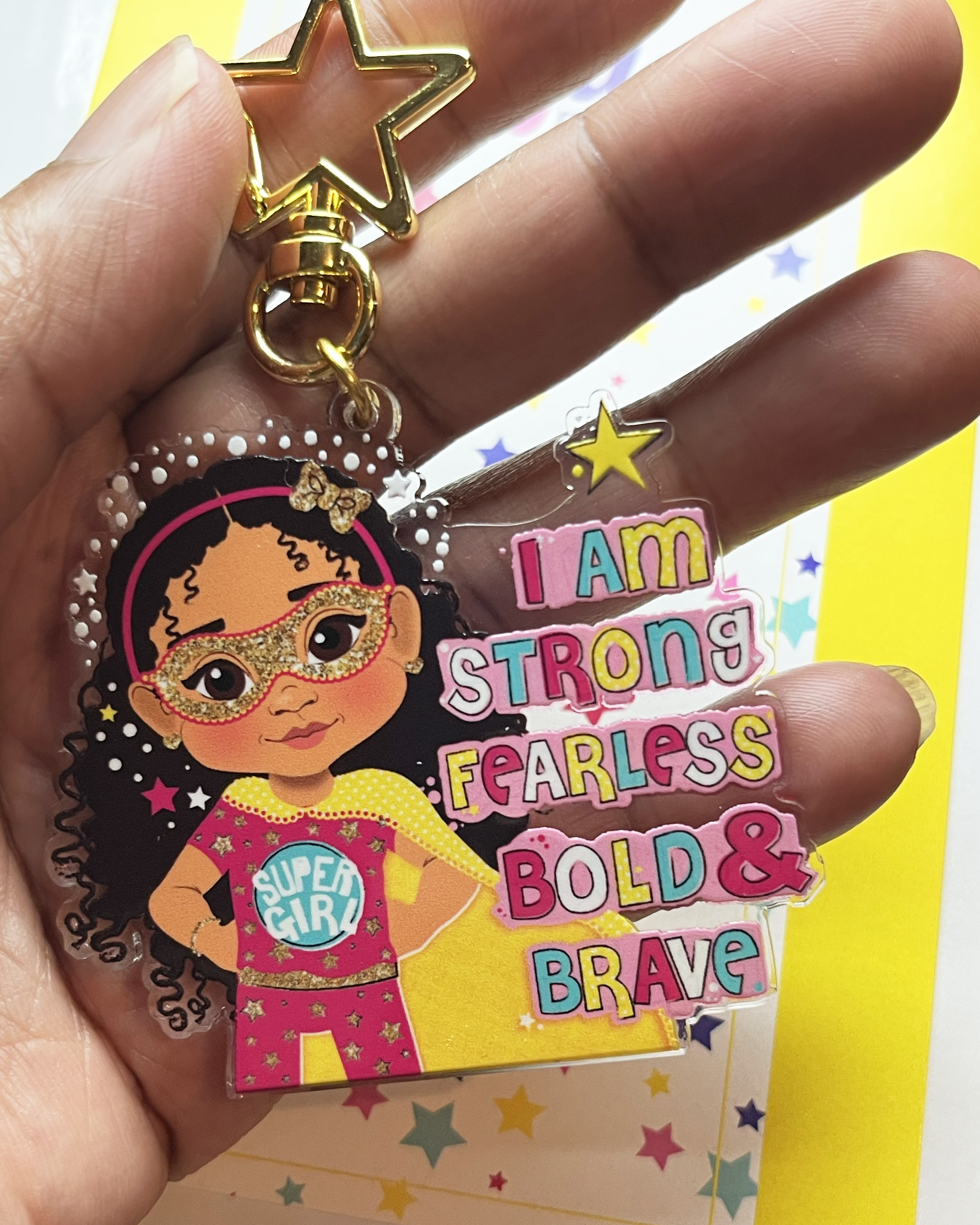 Brown girl superhero keyring with afro hair – empowering recycled kids charm. Keychain with brown girl character and motivational text on a pink background
