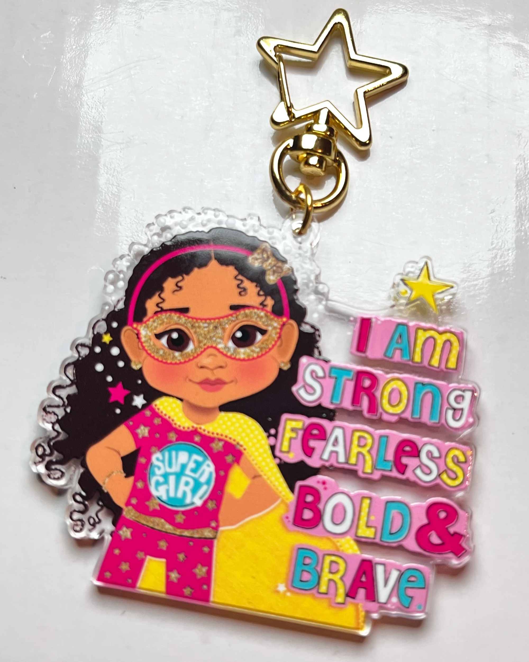 Keychain with a cartoon character wearing a superhero outfit and motivational text on a white background