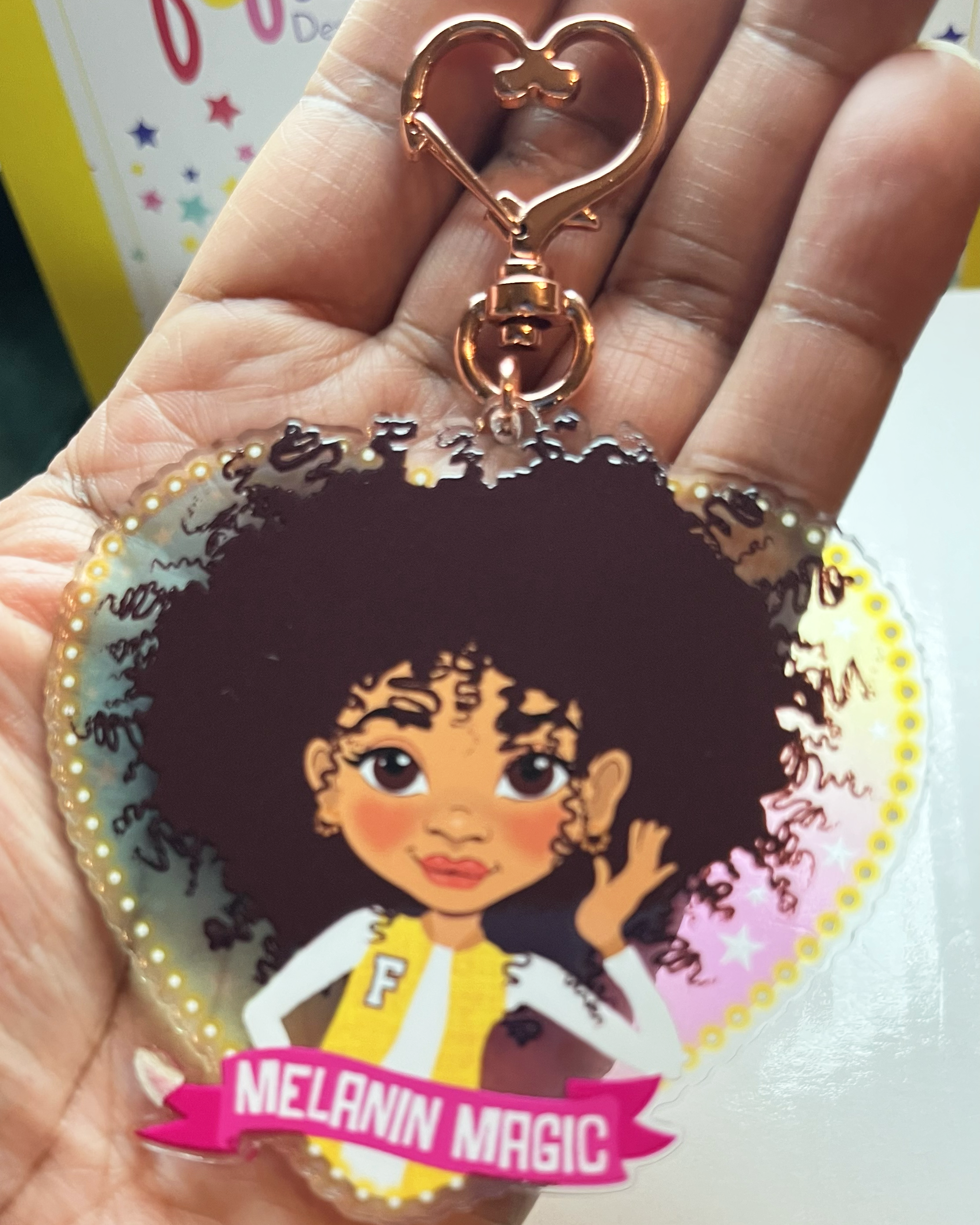 Heart-shaped keychain with a Mixed race Afro Girl hand drawn  character and 'Melanin Magic' text on a banner scroll. Brown tween / teen Girl  keyring with curly afro and “Melanin Magic” affirmation