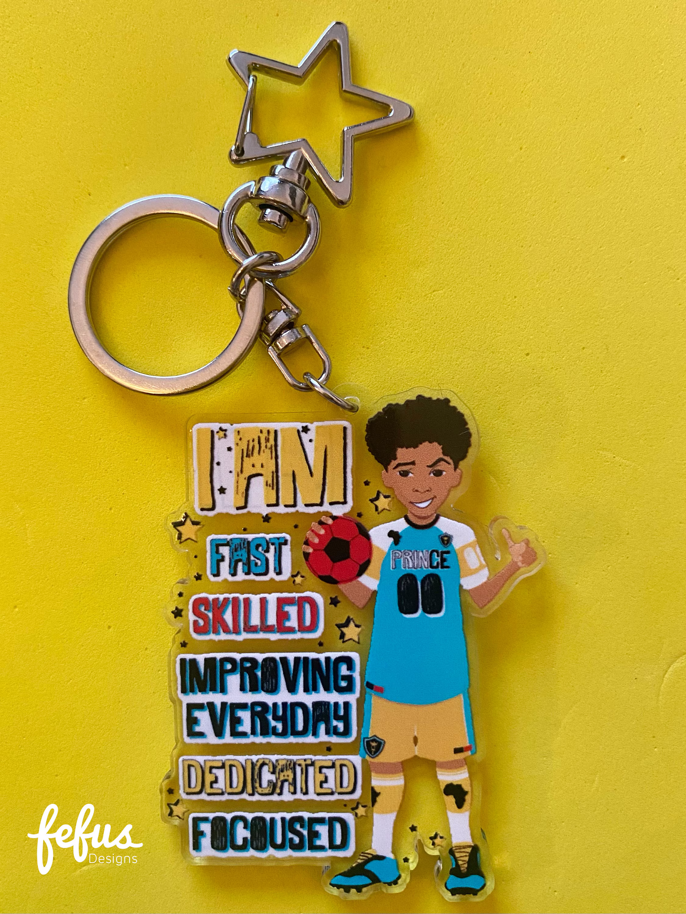Colorful bag charm featuring a hand-drawn illustration of a biracial boy playing football. Made in the UK from sturdy clear acrylic with a double-sided design. (Biracial Boy Footballer Keyring, 2.5 inches)