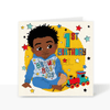 A vibrant and colourful square 1st birthday greeting card for boys, featuring an hand-drawn illustration of a joyful black boy smiling, with the text "1st Birthday" printed on a bright background. He's wearing a blue tracksuit, with the wording Brown Boy Joy on the front of the sweatshirt, he's surrounded by stars and a train by his feet.